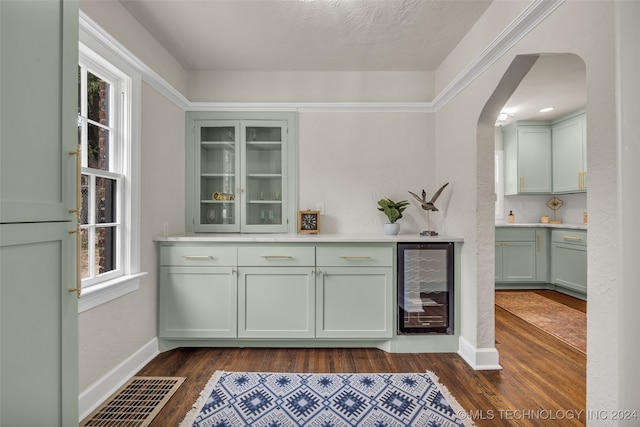 bar featuring beverage cooler, green cabinets, a textured ceiling, and dark hardwood / wood-style floors