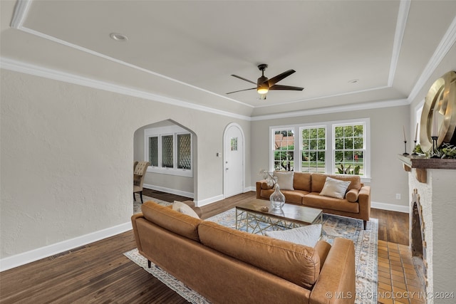 living room featuring ceiling fan, a tray ceiling, dark hardwood / wood-style floors, and crown molding