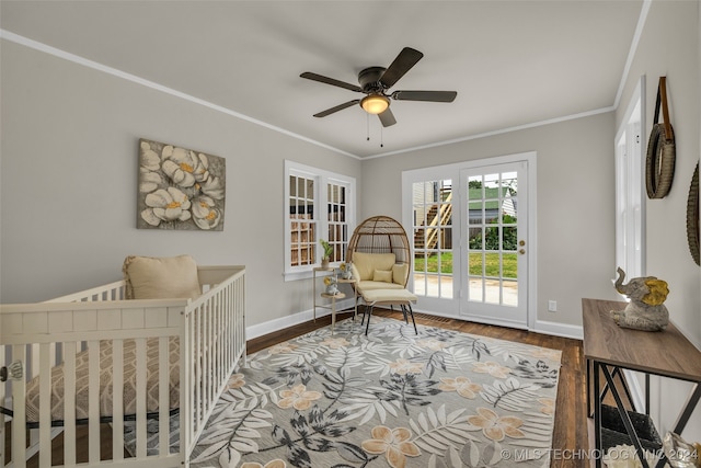 bedroom with ornamental molding, ceiling fan, a nursery area, and hardwood / wood-style floors