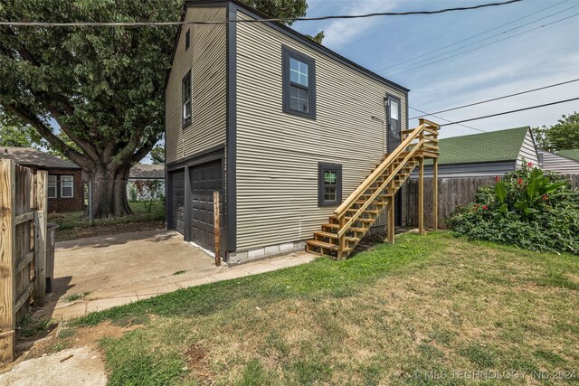 rear view of house featuring a lawn and a garage