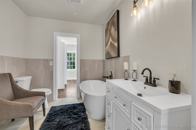 bathroom featuring tile walls, wood-type flooring, a bathtub, and vanity