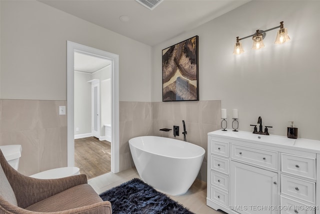 bathroom with vanity, a bathtub, tile walls, and hardwood / wood-style flooring