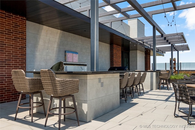 view of patio / terrace with an outdoor kitchen, an outdoor bar, and a pergola