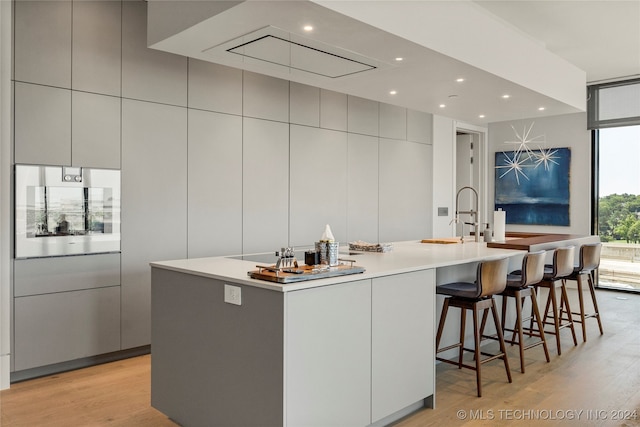 kitchen featuring a large island, gray cabinets, a kitchen breakfast bar, and light hardwood / wood-style flooring