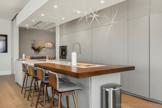 kitchen with light wood-type flooring and a large island with sink