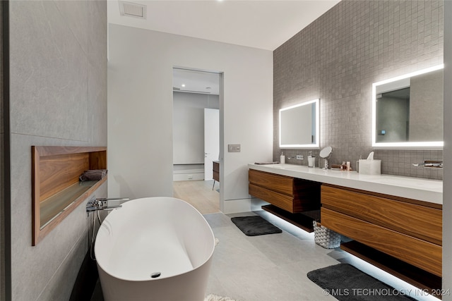 bathroom featuring vanity, tile walls, a washtub, and tile patterned floors