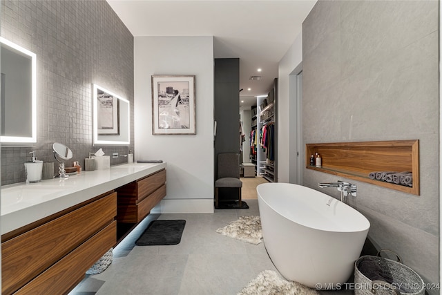 bathroom with tile walls, tile patterned flooring, vanity, and a bathing tub