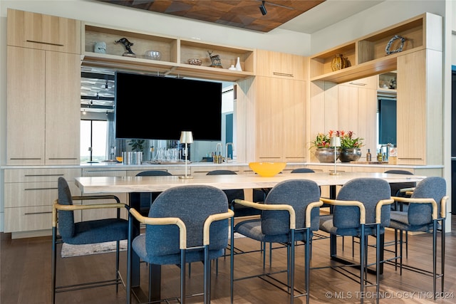 kitchen with a kitchen bar, light brown cabinets, kitchen peninsula, and dark hardwood / wood-style flooring