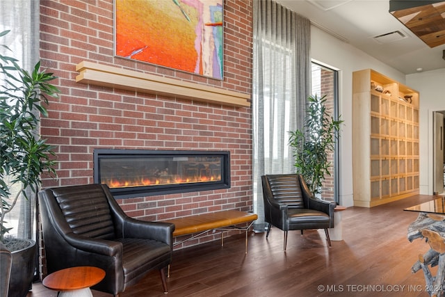 sitting room with a brick fireplace and wood-type flooring