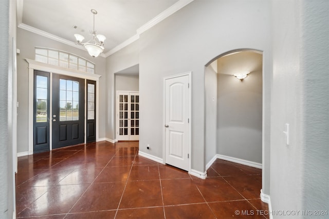 tiled entryway featuring a chandelier and crown molding