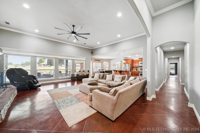 tiled living room featuring ceiling fan, crown molding, and a high ceiling