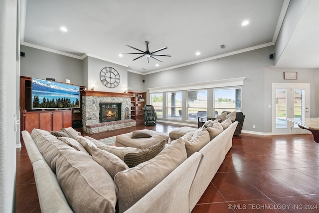 tiled living room with ceiling fan, a stone fireplace, crown molding, and french doors