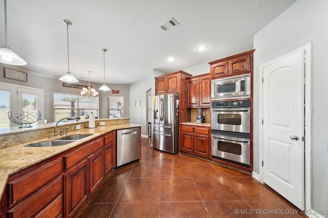 kitchen featuring appliances with stainless steel finishes, light stone countertops, an inviting chandelier, decorative light fixtures, and sink