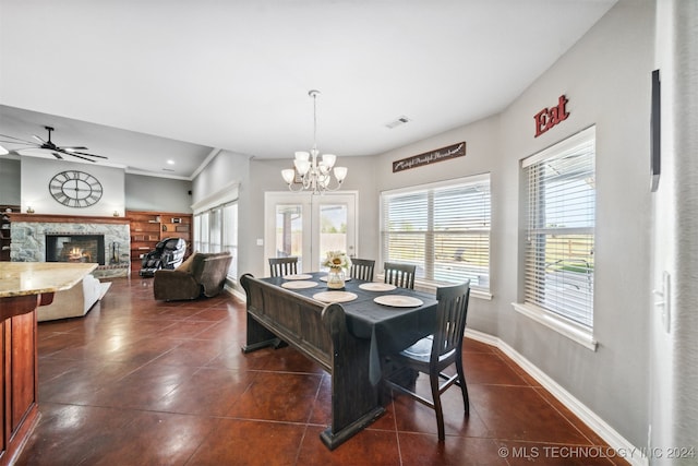 tiled dining area with a stone fireplace, ceiling fan with notable chandelier, and ornamental molding