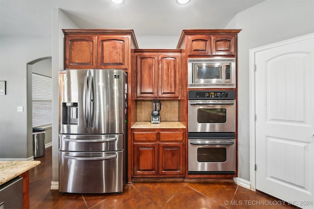 kitchen featuring dark tile patterned flooring, appliances with stainless steel finishes, and light stone counters