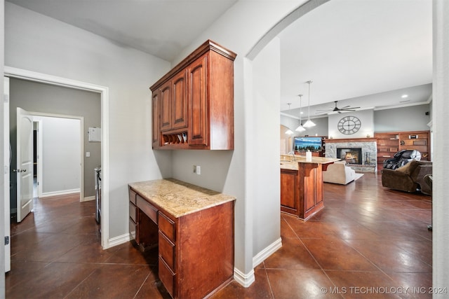 kitchen featuring ceiling fan, pendant lighting, dark tile patterned floors, a breakfast bar, and a fireplace