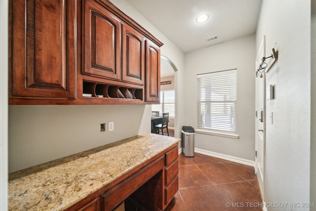 kitchen with light stone countertops and dark tile patterned flooring