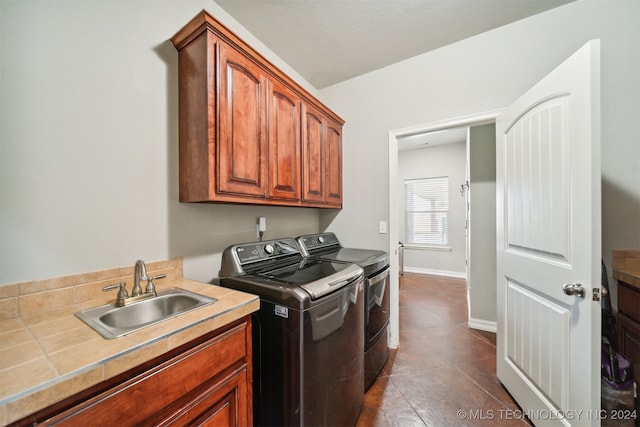 washroom featuring a textured ceiling, cabinets, sink, washing machine and clothes dryer, and tile patterned floors