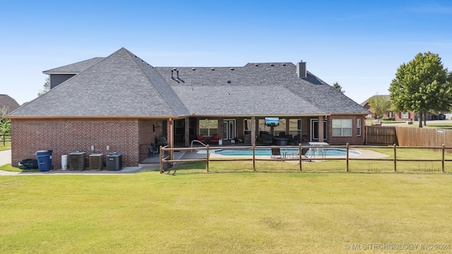 rear view of house featuring a lawn, a fenced in pool, and a patio area