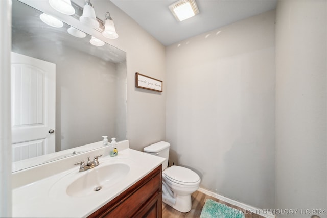 bathroom with vanity, toilet, and hardwood / wood-style flooring