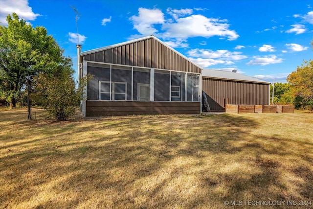 rear view of property featuring a yard and a sunroom