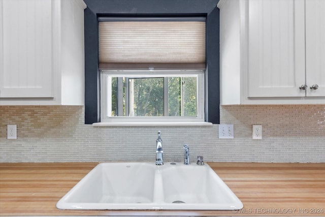 kitchen featuring white cabinets, tasteful backsplash, a sink, and light countertops