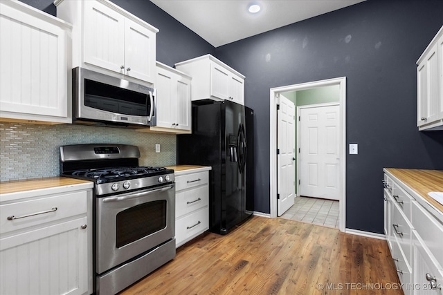 kitchen with appliances with stainless steel finishes, backsplash, light wood-type flooring, and white cabinetry