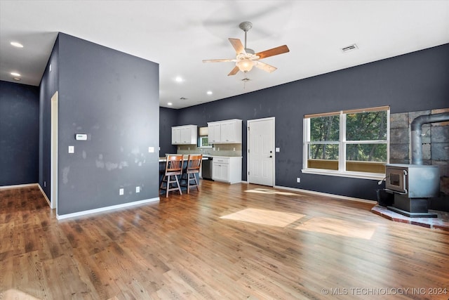 living area featuring ceiling fan, visible vents, wood finished floors, and a wood stove