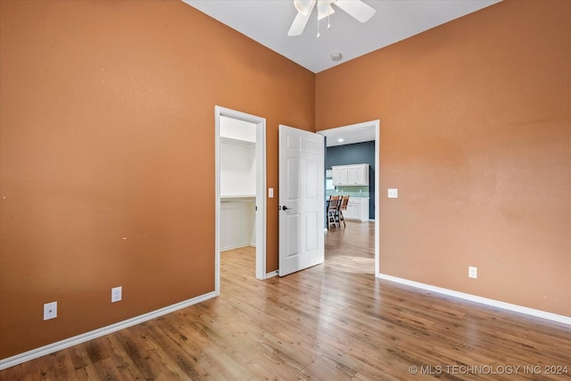 spare room featuring baseboards, ceiling fan, wood finished floors, and a towering ceiling