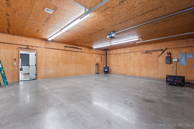 garage with a garage door opener, wooden walls, and electric panel