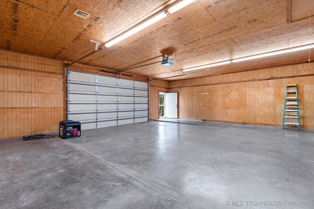 garage with a garage door opener and wood walls