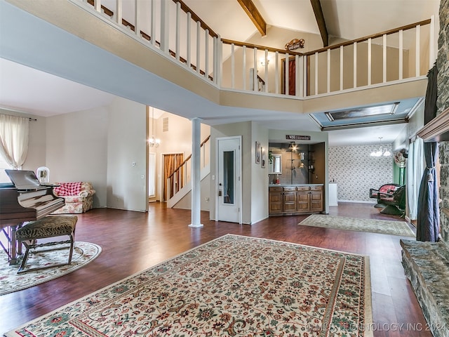 entryway with a towering ceiling, a notable chandelier, dark hardwood / wood-style floors, and beam ceiling