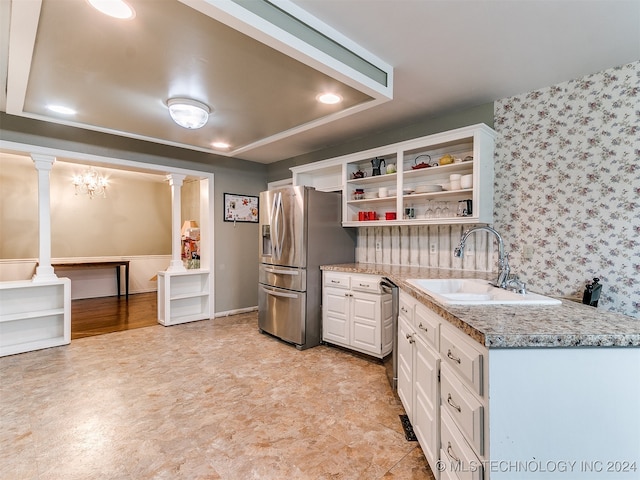 kitchen featuring stainless steel fridge, ornate columns, white cabinetry, and sink