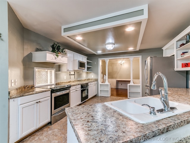 kitchen featuring white cabinetry, a raised ceiling, stainless steel appliances, ornate columns, and sink