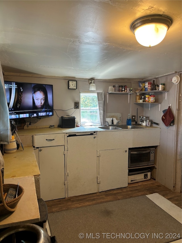 kitchen featuring white cabinets, wooden walls, and dark hardwood / wood-style flooring