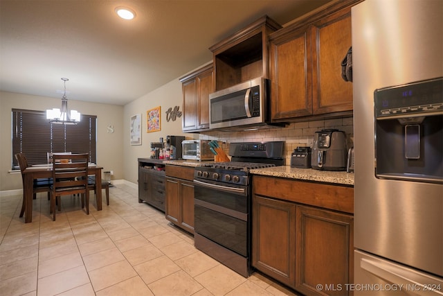 kitchen featuring hanging light fixtures, stainless steel appliances, light stone counters, a notable chandelier, and backsplash