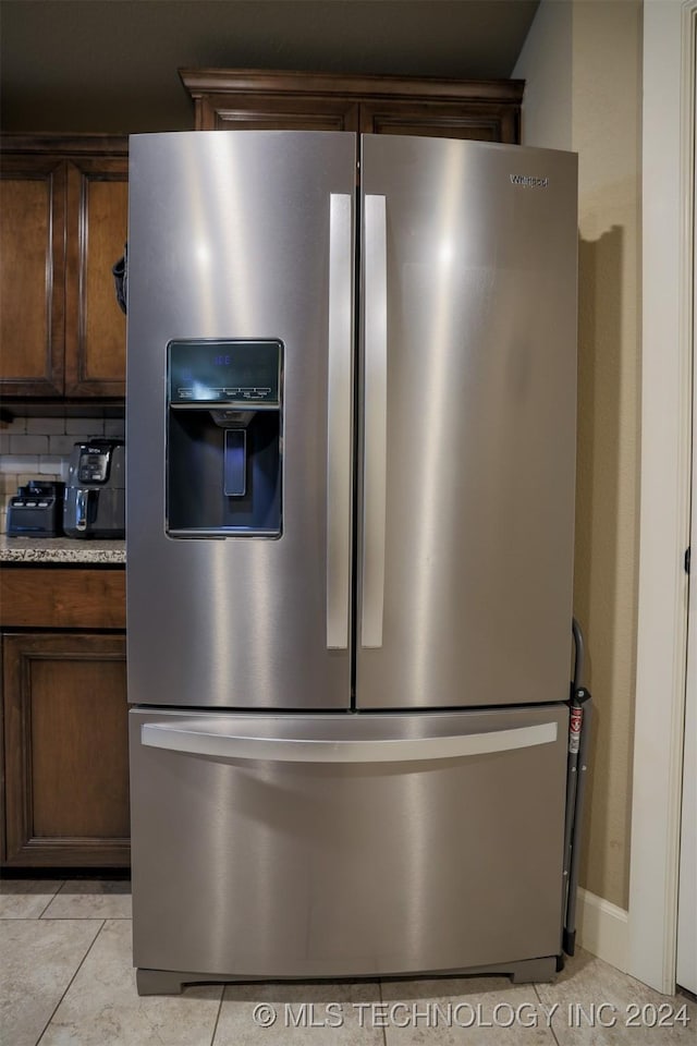 interior details with stainless steel fridge with ice dispenser, tasteful backsplash, and dark brown cabinets