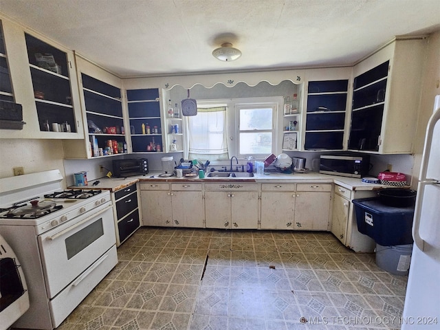 kitchen featuring a textured ceiling, white appliances, and sink