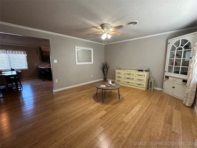 living area with ornamental molding, ceiling fan, hardwood / wood-style flooring, and a textured ceiling