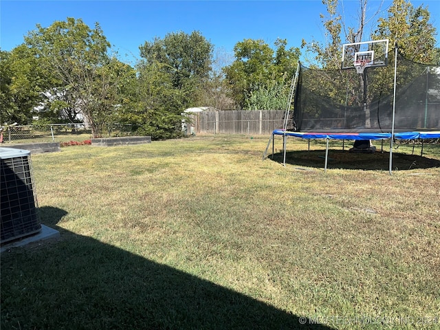 view of yard featuring a trampoline and central AC unit