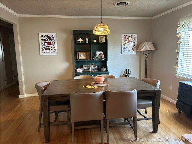 dining area featuring ornamental molding, a textured ceiling, and hardwood / wood-style floors