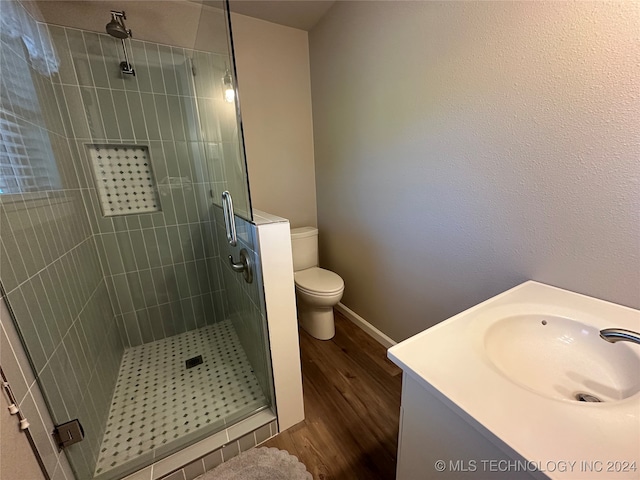 bathroom featuring hardwood / wood-style flooring, vanity, toilet, and a shower with shower door