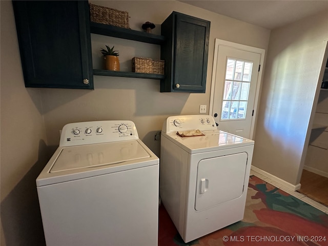 clothes washing area with washing machine and dryer and cabinets