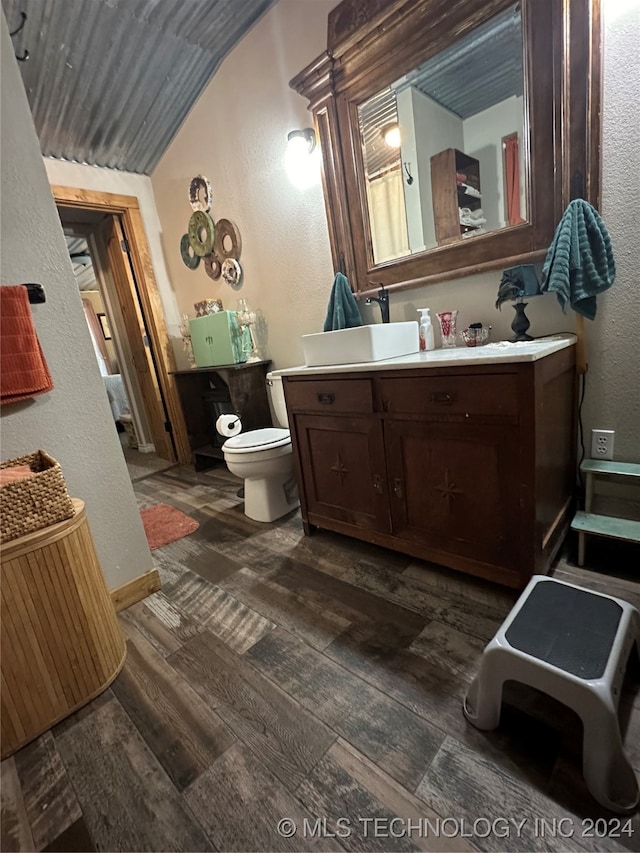 bathroom featuring vaulted ceiling, vanity, hardwood / wood-style floors, and toilet