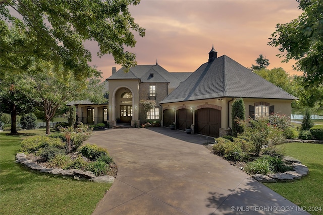 french country style house featuring a yard and a garage