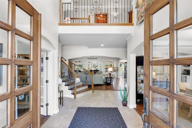 foyer entrance with a towering ceiling, light hardwood / wood-style floors, and crown molding