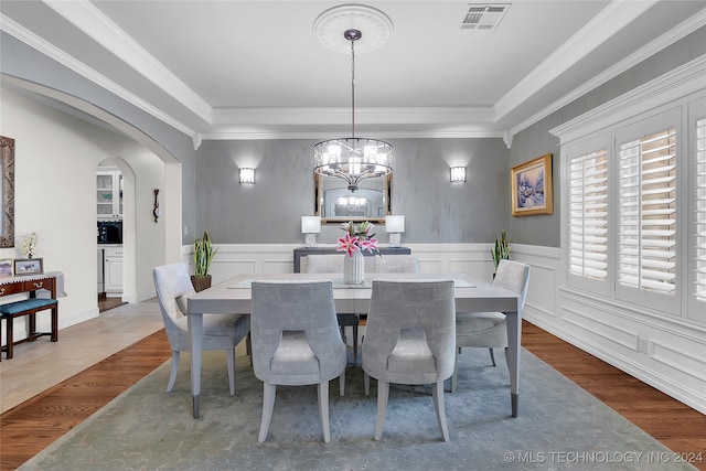 dining space with wood-type flooring, a notable chandelier, and crown molding