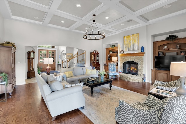 living room featuring coffered ceiling, dark wood-type flooring, a fireplace, beam ceiling, and a notable chandelier