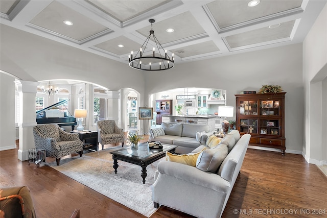 living room with a notable chandelier, beam ceiling, dark wood-type flooring, and ornate columns