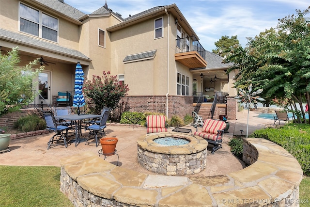 view of patio / terrace with a balcony, ceiling fan, and a fire pit